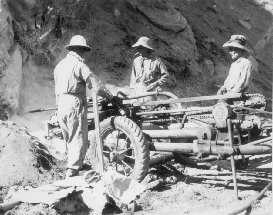 Image of three men working with construction equipment at Kooskia Internment Camp. Photo taken from 12-3/4 x 15-1/4 Photograph album of the Kooskia Japanese Internment Camp.