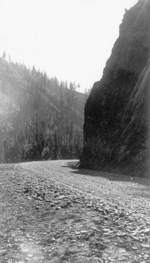Image of a gravel road at a bend in the road at Kooskia Internment Camp. Photo taken from 12-3/4 x 15-1/4 Photograph album of the Kooskia Japanese Internment Camp.