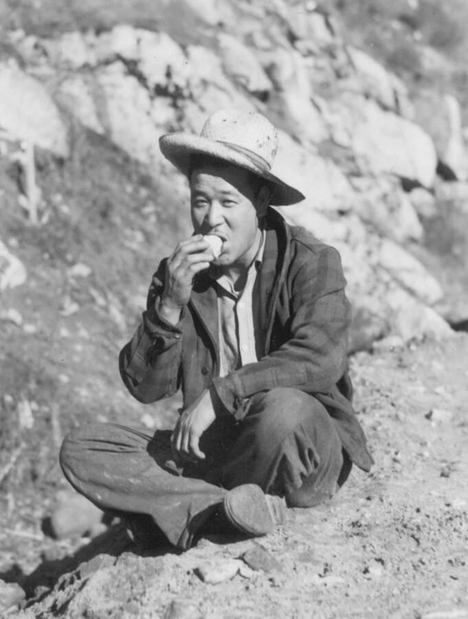 Image of man sitting and eating at Kooskia Internment Camp. Photo taken from 12-3/4 x 15-1/4 Photograph album of the Kooskia Japanese Internment Camp.