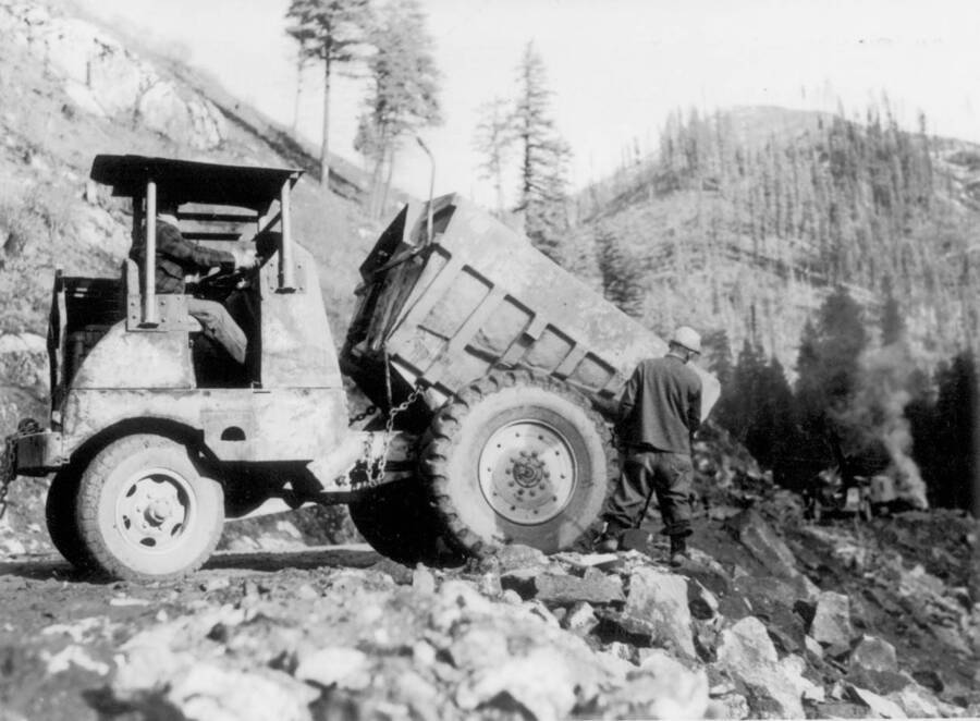 Image of two men working with dump truck at Kooskia Internment Camp. Photo taken from 12-3/4 x 15-1/4 Photograph album of the Kooskia Japanese Internment Camp.