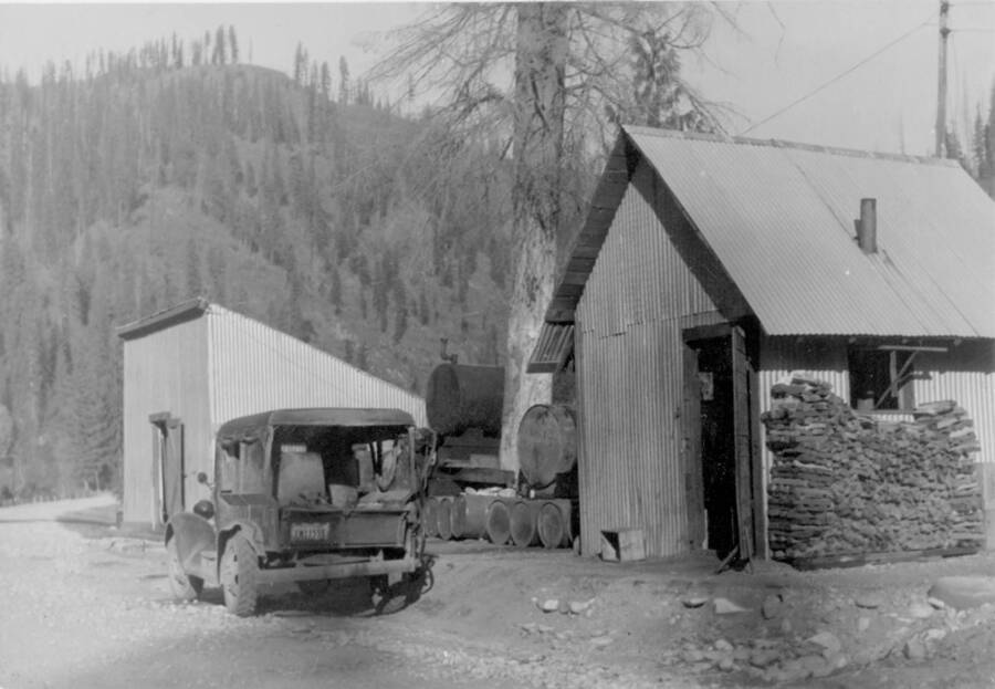 Image of Kooskia Internment Camp vehicle and buildings. Photo taken from 12-3/4 x 15-1/4 Photograph album of the Kooskia Japanese Internment Camp.