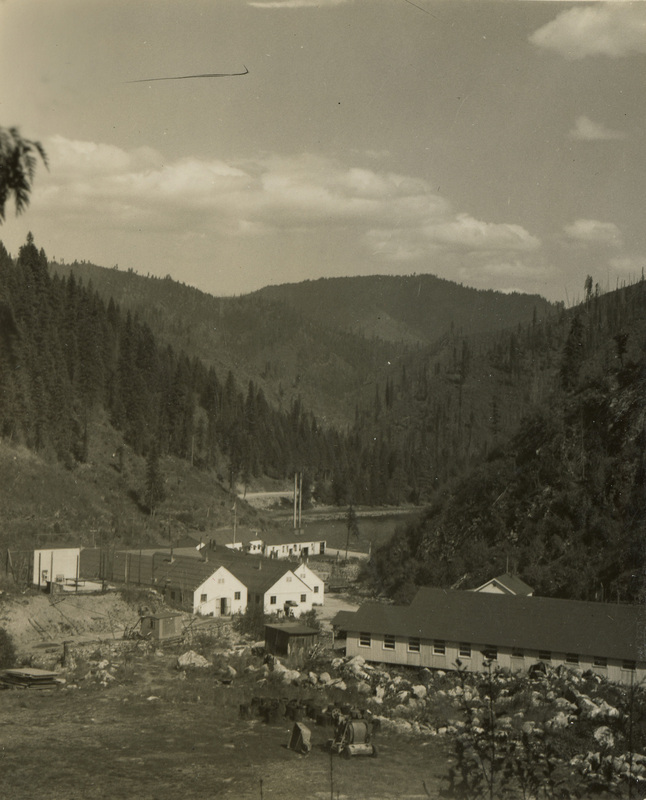 A black and white photograph the Lochsa River and Kooskia camp building in the foreground.