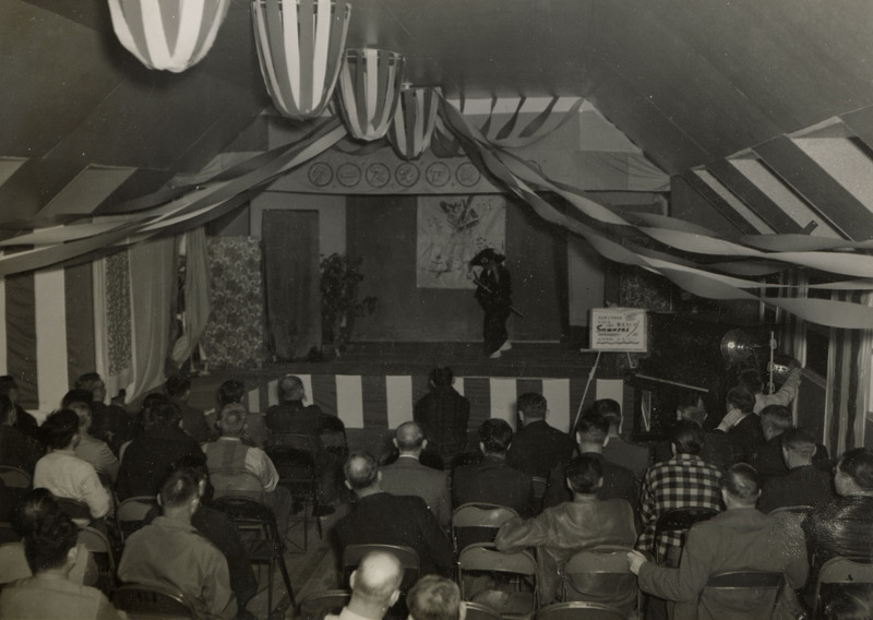 A black and white photograph of a stage production held indoors. The actors are dressed in traditional Japanese clothing.