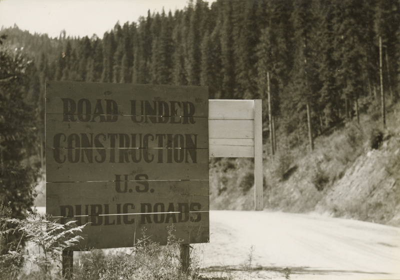 A black and white photograph of a sign. The text reads "Road Under Construction. U.S. Public Roads".