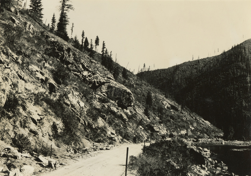 A black and white photograph of a hillside and dirt road.