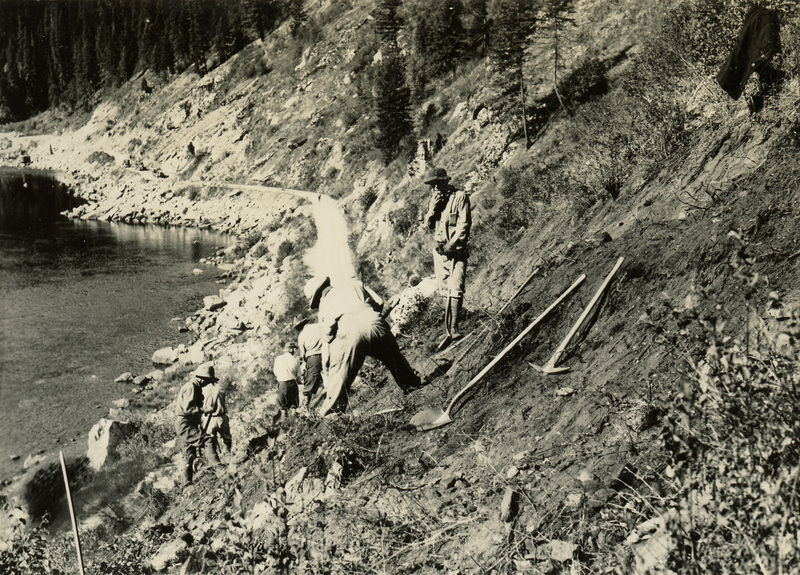 A black and white photograph of men digging along a hillside with pickaxes and shovels.
