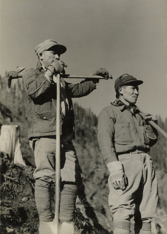 A black and white photogrpah of two men with shovels and pickaxes.