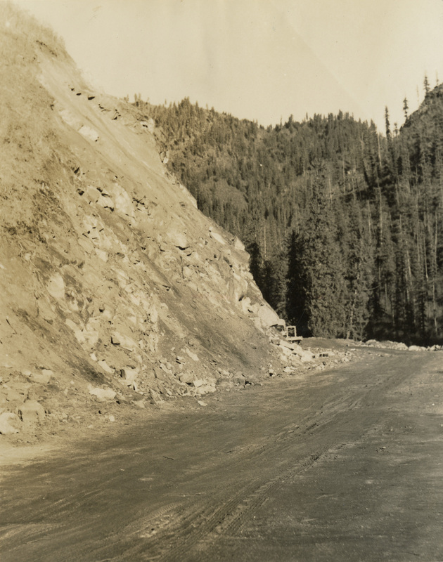 A black and white photograph of a dirt road.
