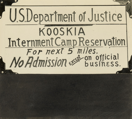 A black and white photo of a sign from the Kooskia Internment Camp. It reads "US Department of Justice. Kooskia. Internment Camp Reservation. For next 5 miles. No Admission except on official business."