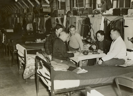 A black and white photograph of men sitting around a table playing games.