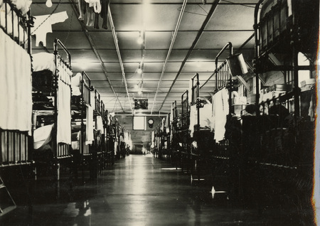 A black and white photograph of the interior of a building at Kooskia. There are rows of bunk beds in a long building.