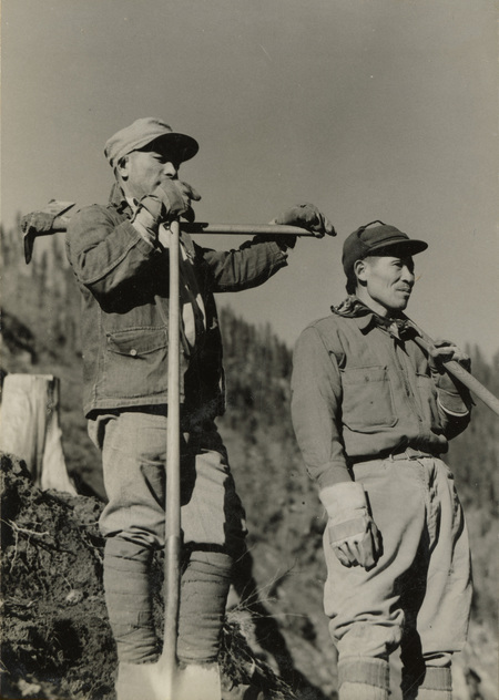 A black and white photogrpah of two men with shovels and pickaxes.