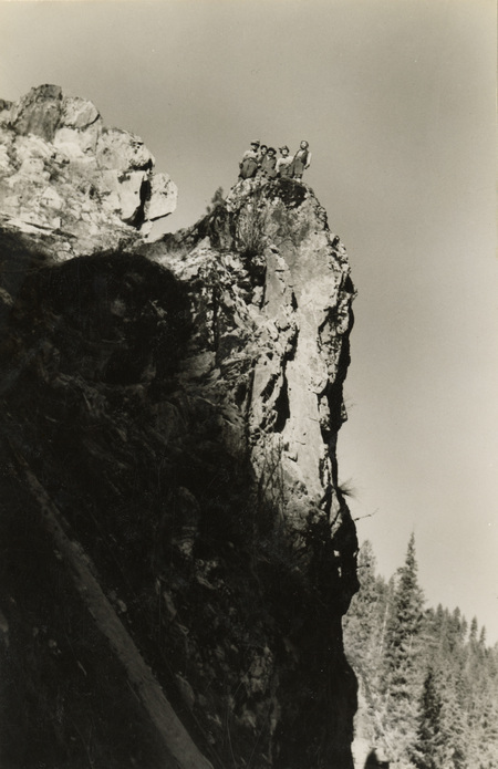 A black and white photograph of five men standing on the top of a cliff.
