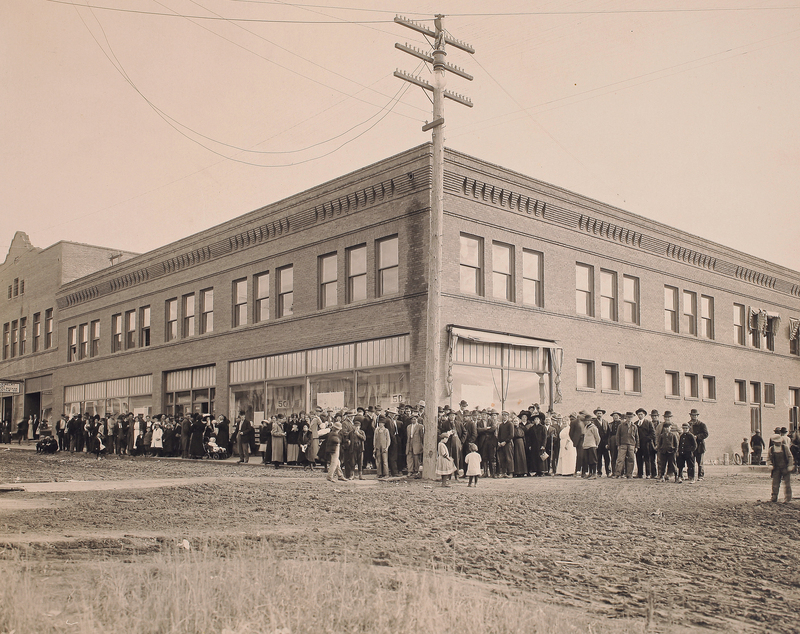 Large crowd standing outside the Potlatch Mercantile located in the Potlatch Commercial Historic District.