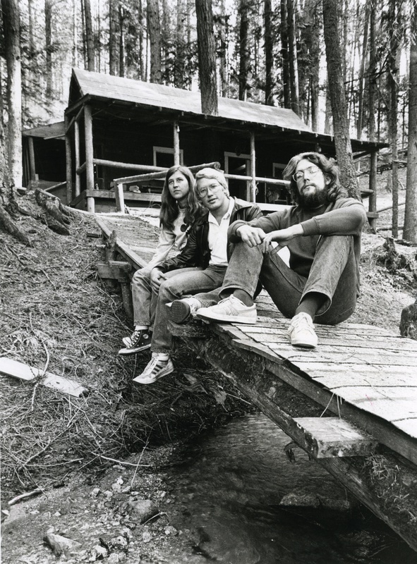 Three unidentified people sitting on a bridge at Idler's Rest Nature Preserve. This was before the cabin was torn down.