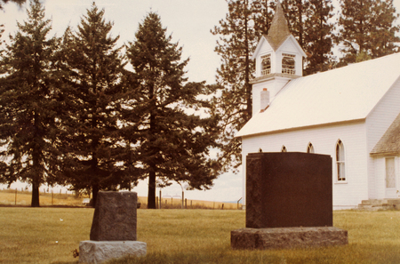 Image depicting the Elwood Cemetery gate and three tombstones.
