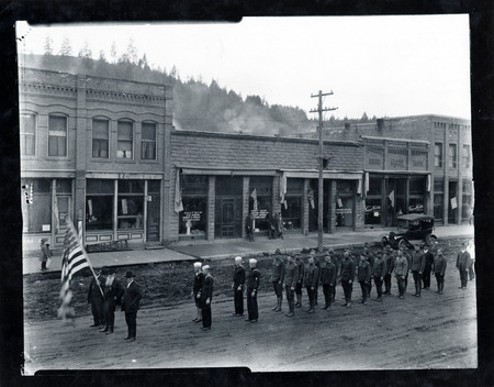 Historic view of downtown Troy, ID during an Armistice Day Parade. The Hotel Rietmann can be partially seen (first building on left).