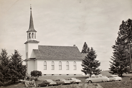 People walking inside the Genesee Valley Lutheran Church. Cars parked out front.