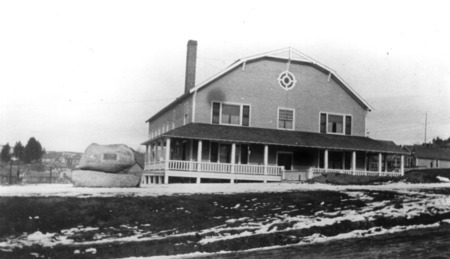 Historic image of the Gymnasium in Potlatch, ID. The William Deary memorial monument showing two boulders with a plaque mounted on top boulder.