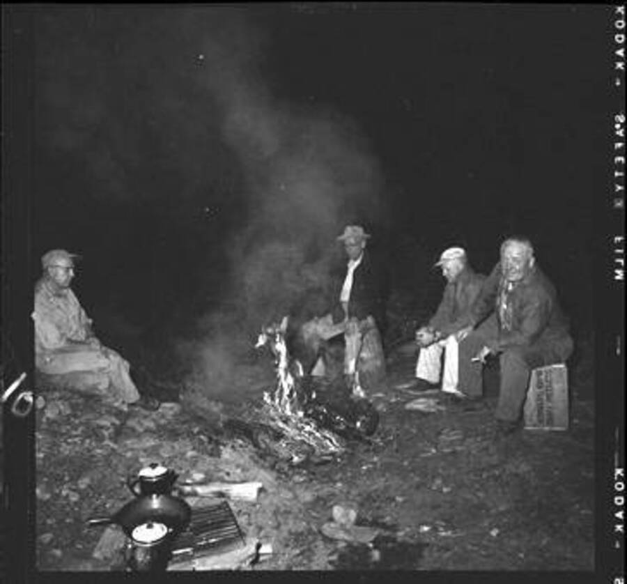 Men sitting around fire at campsite on Meadow Creek