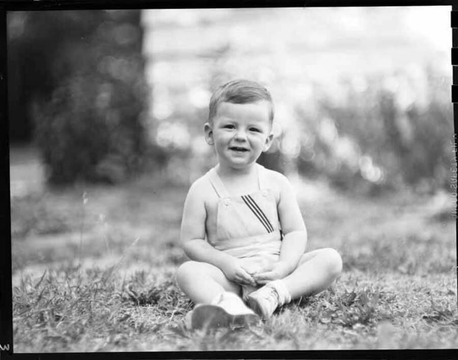 Image shows Beezie, as a child, sitting on the grass.
