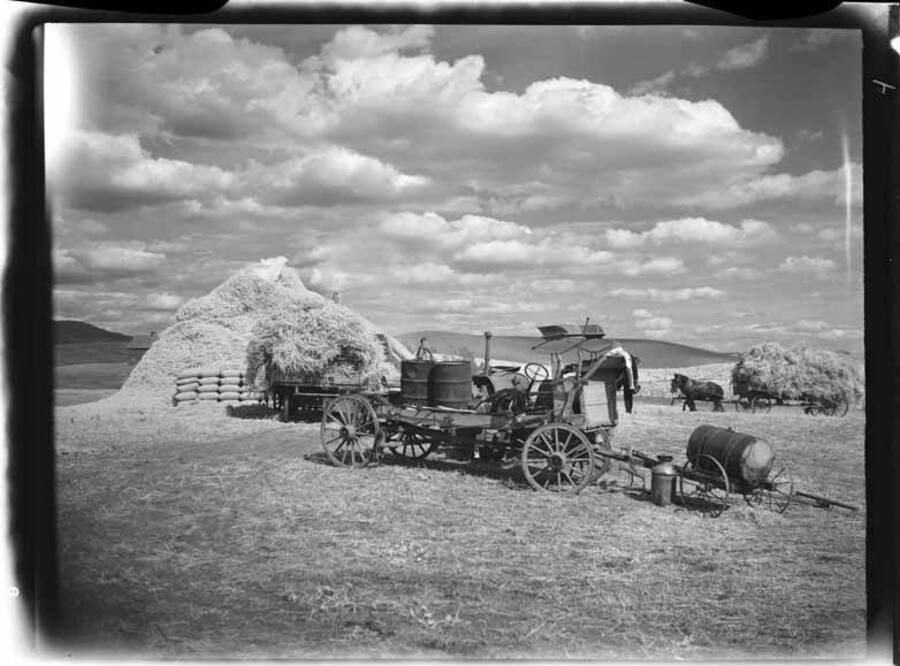 Images shows harvest scene with hay stacks with horses and wagons.