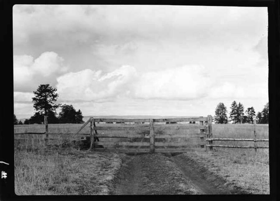 Image shows a wood gate on across a dirt road in the Joseph Plains region of Idaho.