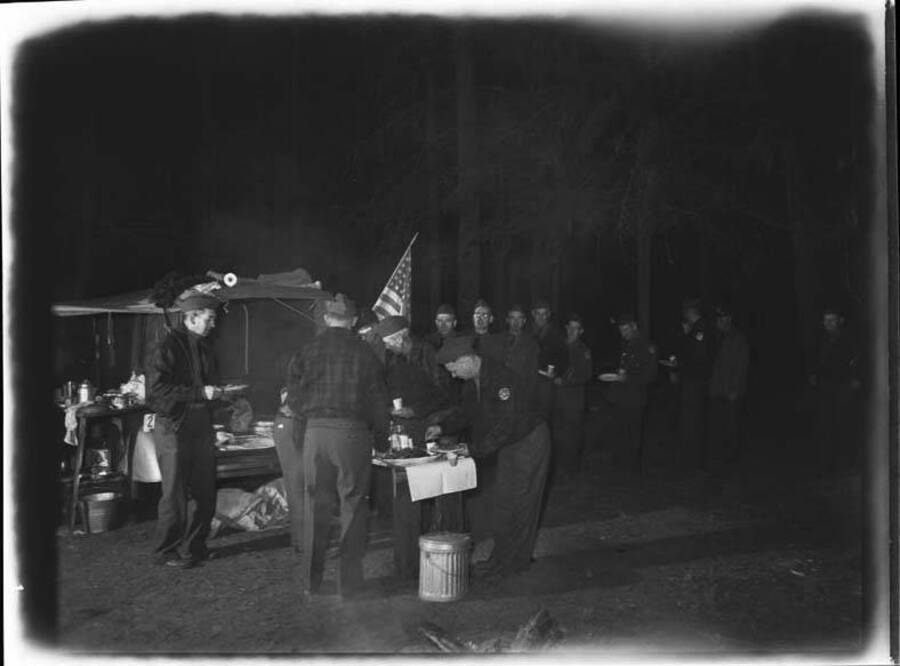 An evening image of National Guardsmen lining up for dinner on a trip.