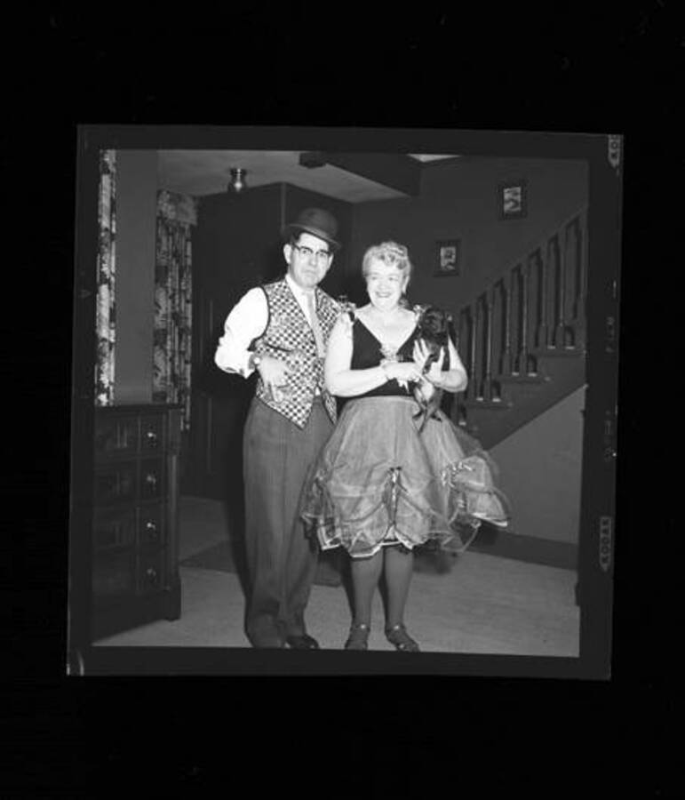 Two persons dressed in costumes for a party. Woman is holding Jimminy Crickets, the Laughlin family dog.