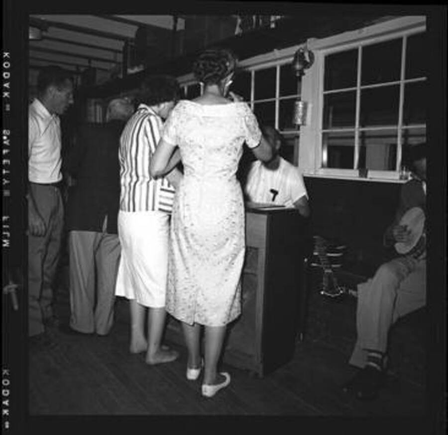 Unidentified persons standing around the piano at a dance at Lake Coeur D'Alene.
