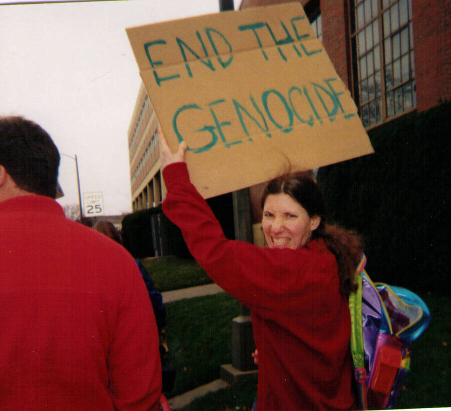 A woman holds a sign reading ""End the Genocide"" during the anti-war rally at the University of Idaho