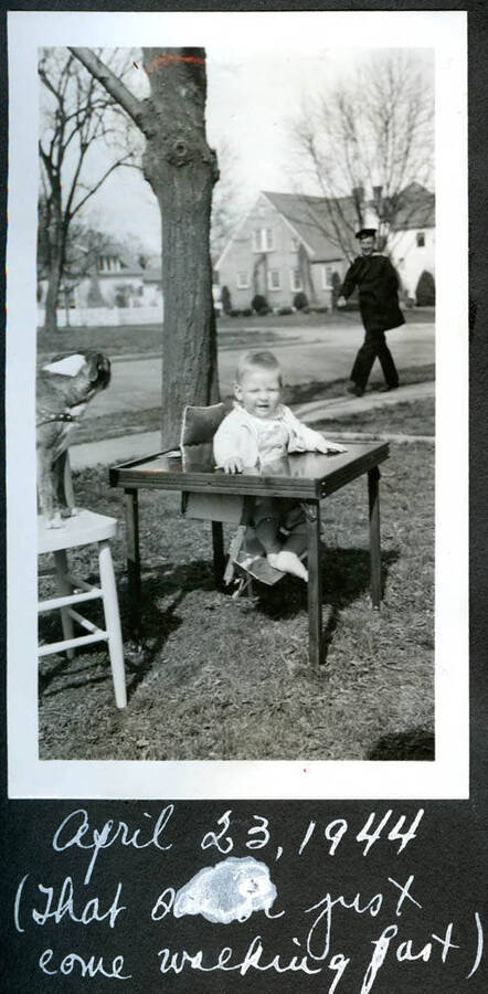 Baby photo of Bill Hopkins outdoors at a table, and with a dog