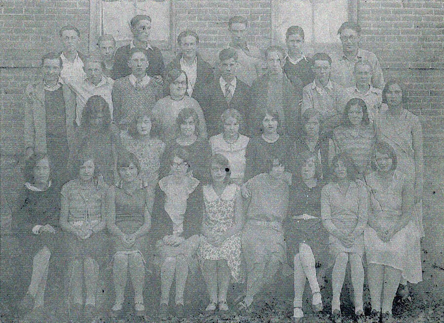 Group photograph of several Palouse high school students. Pictured in the front row from left to right: L. Hilman, G. Kroll, A. Cox, B. Tidwell, E. Emrey, T. Lined, H. Keagle, V. Parish, A. Enyernt. 2nd row: M. Shephard, Luella Palmer, B. McClure, V. Lynch, L. Horton, R. Day, V. Chase, Leona Carscallen. 3rd row: J. Palniter, K. Ogan, D. Jackson, Miss Coon, T. Sanders, V. Anderson, D. Lazelle, C. Hillman. Back row: W. Marsh, T. Boothby, Merle Carscallen, V. Fisher, W. (Bill) Carscallen, B. Couey, V. Barnes.