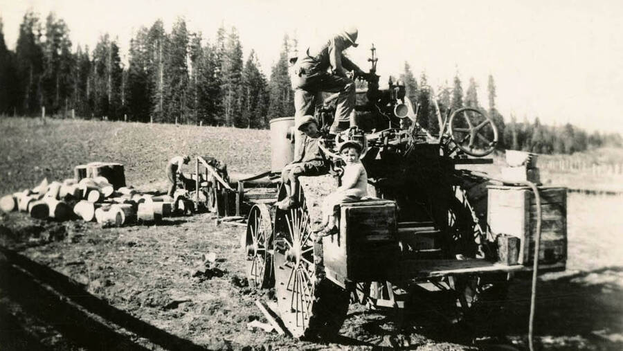 Cutting wood with old swinging buzz saw. Edd Soncarty on top of his steam engine, Lowell and Norman sitting on tractor.