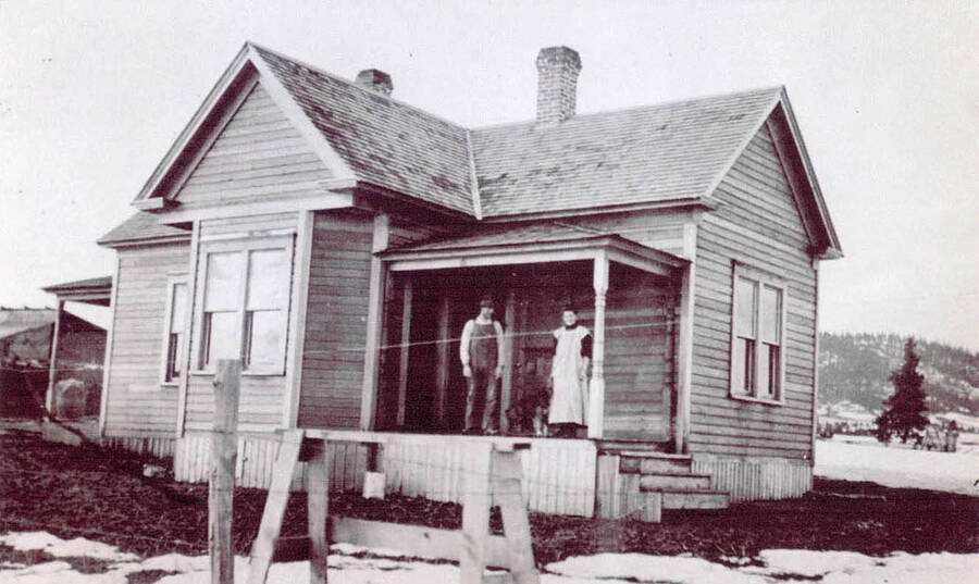 Mr. and Mrs. Sam Clark standing on the porch of a house.