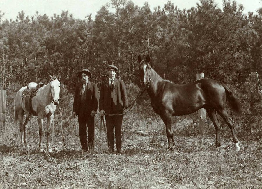 Vern Clark and Archie Clark stand for a photograph with their horses. Vern is on the left and Archie is on the right.