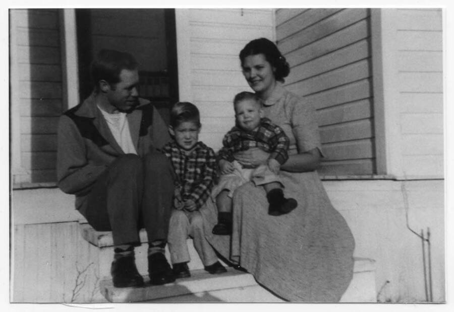 The Fleener family posing for a photo, while sitting on the steps leading up to their house. Names read as subjects appear, left to right: Fleener, Loyal Ivan; Fleener, Craig Loyal; Fleener, Timothy Paul; Fleener, Marva Joyce.