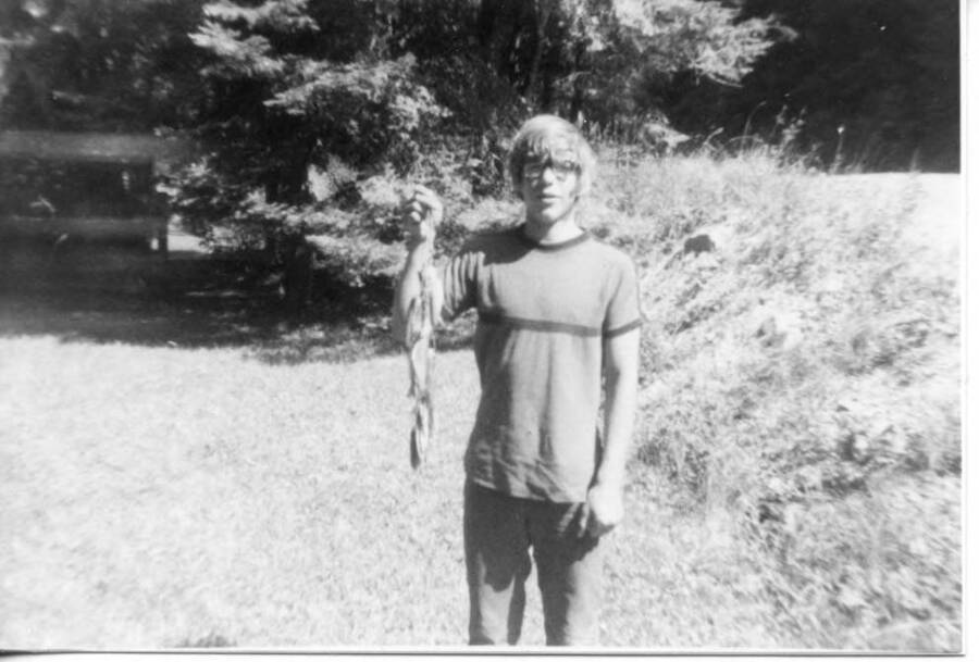 Tim Fleener standing and holding a line of fish he caught.