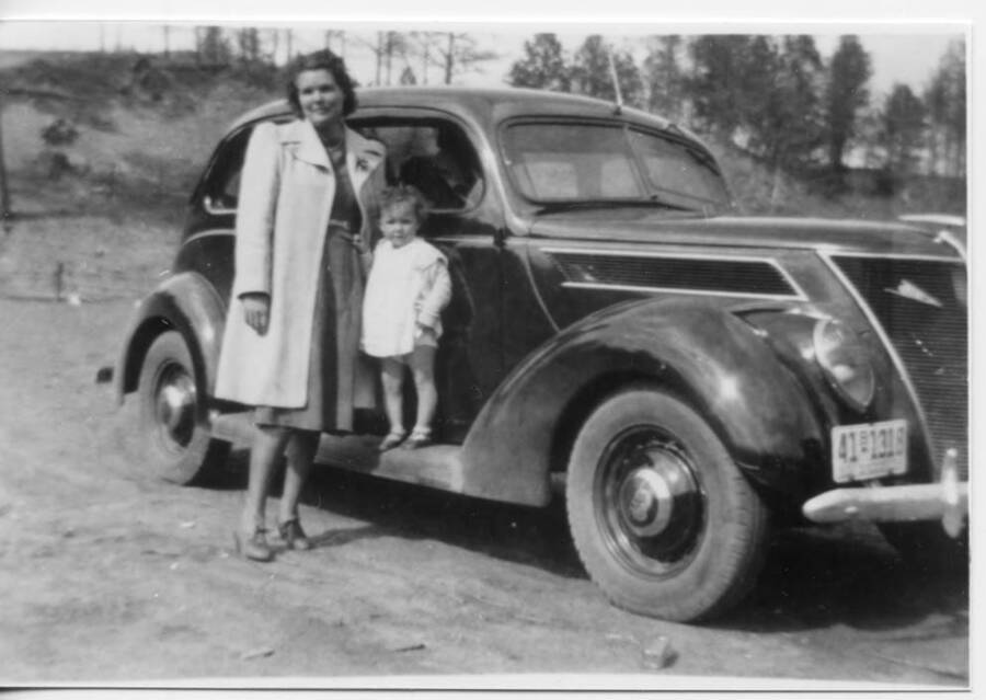 Alice Briney and Marva Joyce Briney standing together in front of a Ford car. Marva Joyce is standing on the side of the car.