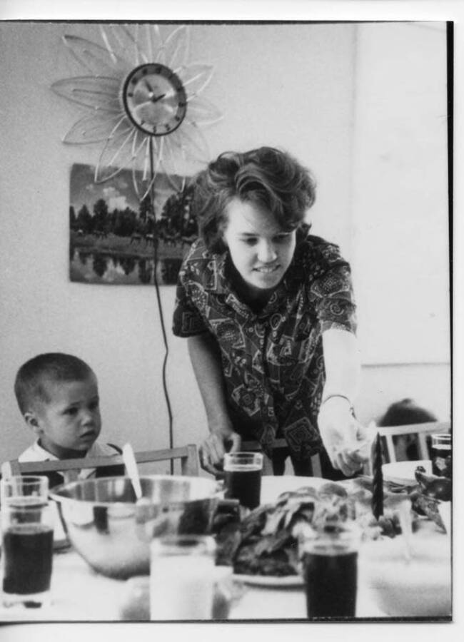 Phillip Fleener and Kathleen Briney at Dora Otter and Ansel Fleener's home, which was located at present day Doug Rudolph home along Estes Road. Kathleen can be seen lighting a candle at the dining table while Phillip watches.