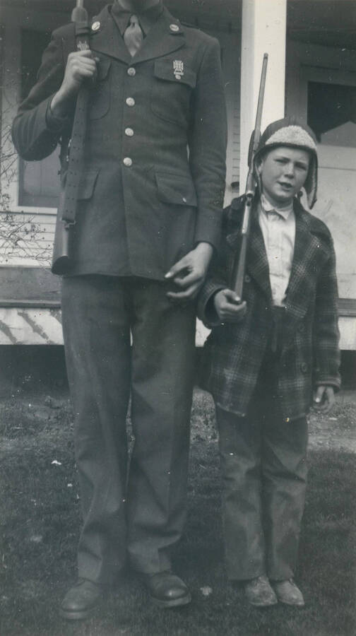 Charles and Danny King holding rifles in front of house