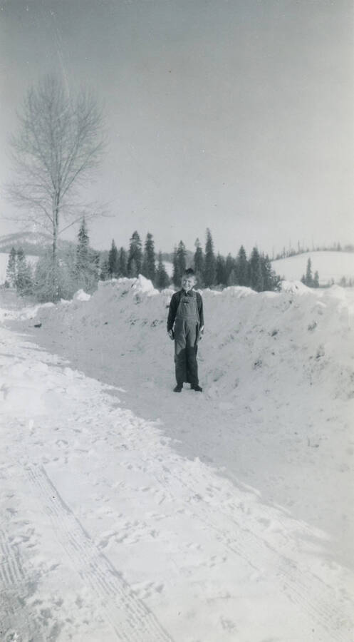 Allen Strong in front of snowbank in winter 1949, in front of house we built along the highway.