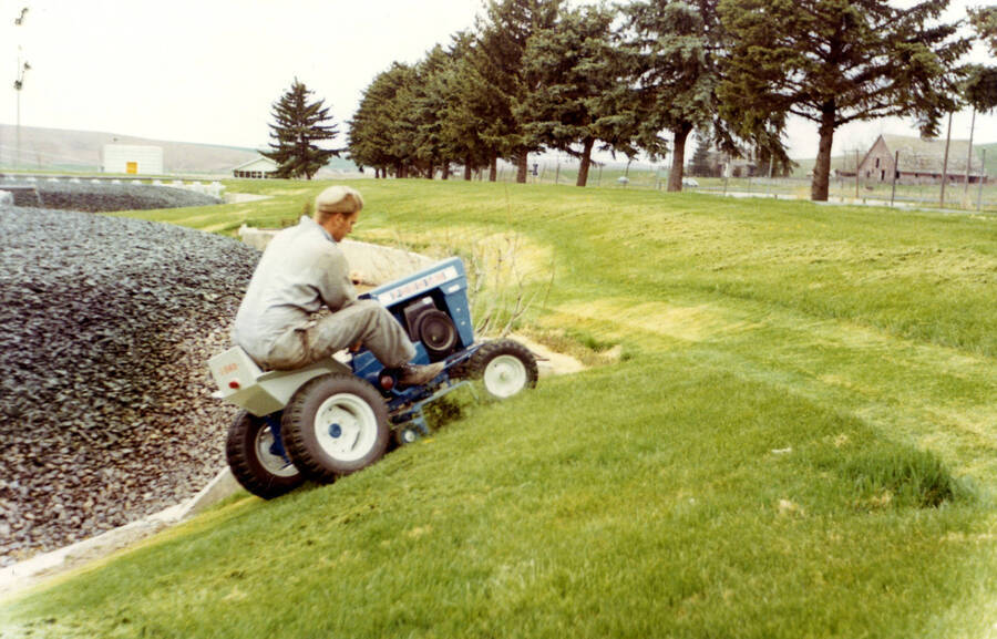 Operator Lyle Brouse mowing around north side of Trickle Filter #1 (pre 1985)