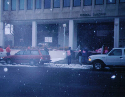 Code Pink War Protest in February 2003. People can be seen holding signs near a pink ribbon across the entrance of the Federal Building in downtown Moscow.