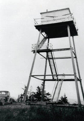 All the material to make the tower was packed up on the mountain with the Forest Service pack mule string. A steel tower later replaced the old wooden tower. Ed Woolverton's pickup sits by the tower.