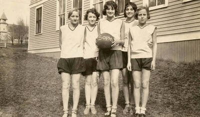 Photograph of the Potlatch sophomore girls basketball team posing in front of the elementary school, basketball in hand. From left to right: Alene Schultz, Beulah Piper, Bertha Beyer, Alene Puckett, Thelma Vasser, and Louise Katzenberger.