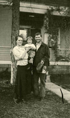 Lois, Will, and Eugene Bysegger standing in front of an unidentified house.