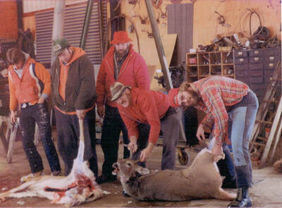 John Rohn, Jerry Rohn, Joe Rohn, Harold Rounds, Ivan Rounds stand for a photograph with their deer in a garage.