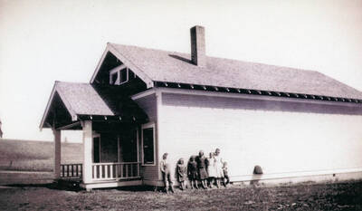 A group of students standing against the wall of the Burden School 3rd school house.