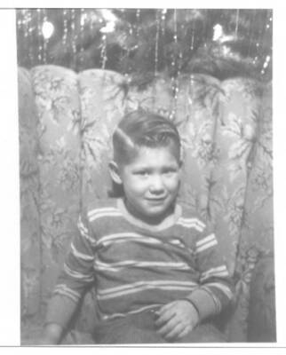 Craig Fleener poses for a Christmas photo. A Christmas tree can be seen standing behind the chair that Craig is sitting in.